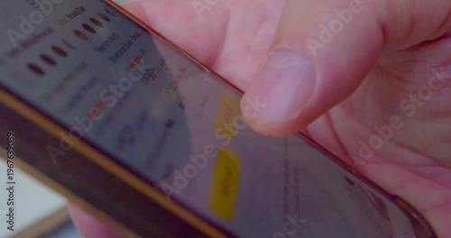 Macro shot of a finger pressing smartphone screen to select sneakers from an online store.