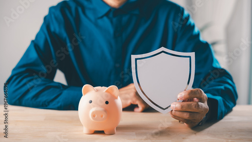 Fotografie Man holding shield next to piggy bank to protect money, save, plan, financial in