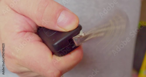 Male hand opening foldable car key, close-up shot with shallow depth of field.