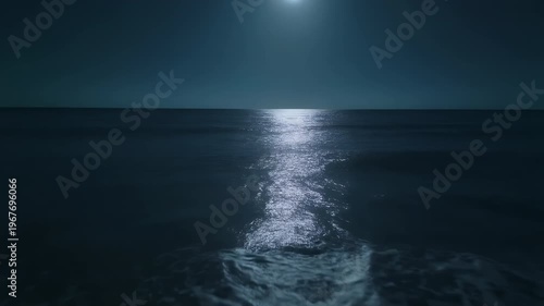 Gentle waves on a moonlit seashore reflecting silvery light in a tranquil blue night