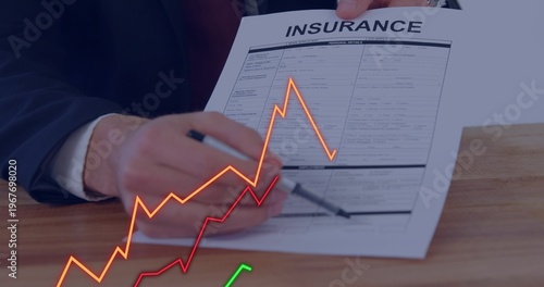 Pointing suited hands highlighting INSURANCE form at office table, with pen and colored graphs