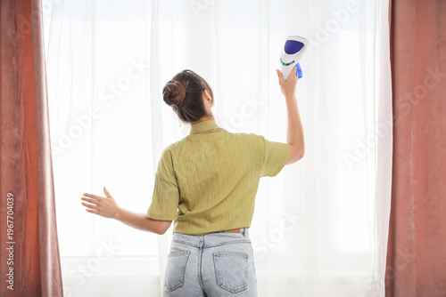 Young woman steaming curtai...