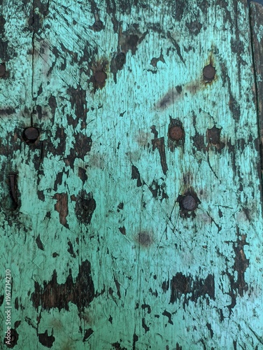 Distressed wooden surface with peeling turquoise paint and dark brown wood