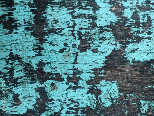 Distressed wooden surface with peeling turquoise paint and dark brown wood
