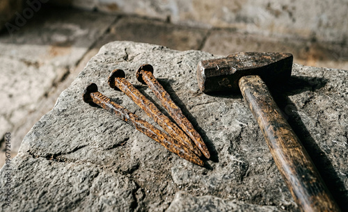 Ancient Rusty Iron Nails and Old Vintage Hammer on Rough Stone Surface