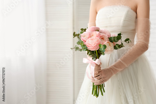 Young woman in wedding dress with bouquet of beautiful ranunculus flowers at home, closeup