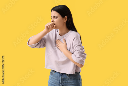 Young woman coughing on yel...