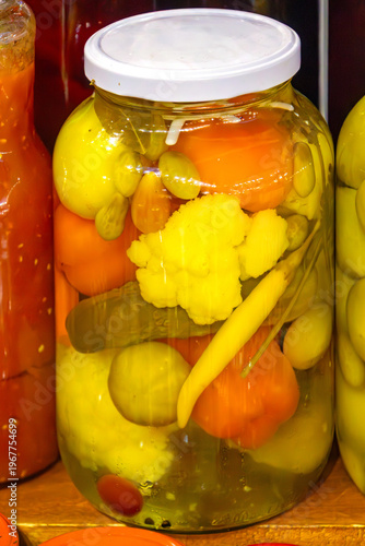 Large closed glass jar filled with organic fermented vegetables in home pantry interior