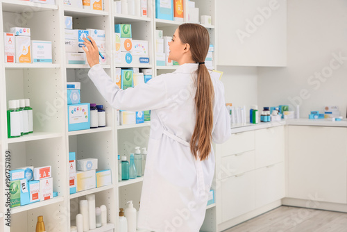 Female pharmacist taking medication from shelf at pharmacy