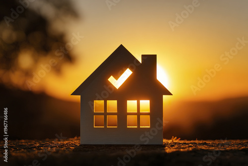 Mortgage approval concept with glowing sunrise behind house silhouette, symbolizing home ownership and real estate success in warm golden light