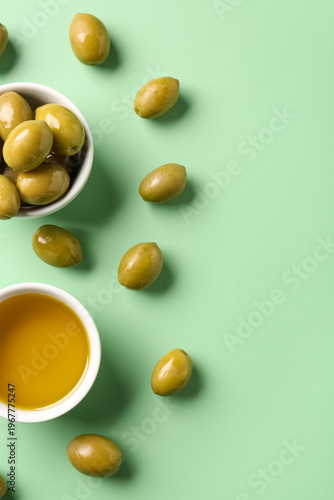 Fotografie Bowls with ripe olives and oil on green background