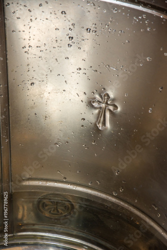 cross printed in a stainless steel vessel at a baptism,Orthodox Church, Romania 