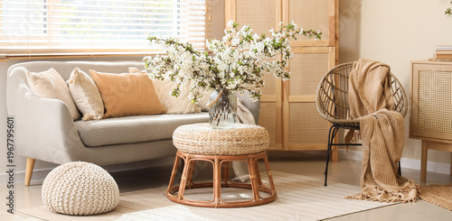 Interior of living room with sofa, folding screen and flowering branches in vase