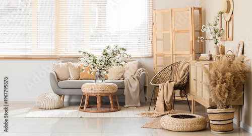Interior of light living room with sofa, armchair and flowering branches