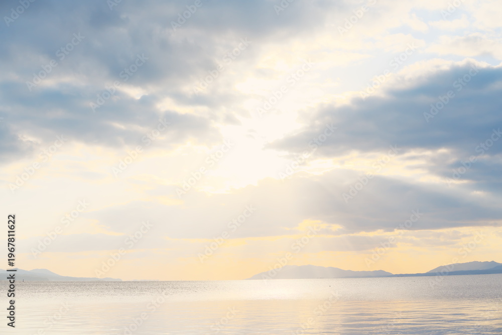 Fototapeta premium 宍道湖の穏やかな水面に夕日が差し込む、遠景の山々