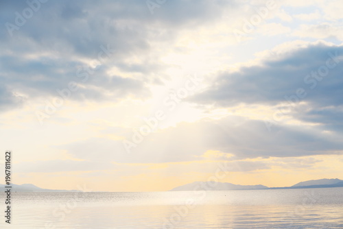 宍道湖の穏やかな水面に夕日が差し込む、遠景の山々