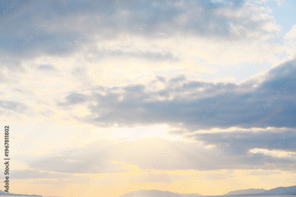 Naklejka premium 雲の隙間から降り注ぐ薄明光線と夕暮れに染まる静かな山並みの風景