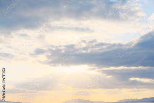 雲の隙間から降り注ぐ薄明光線と夕暮れに染まる静かな山並みの風景