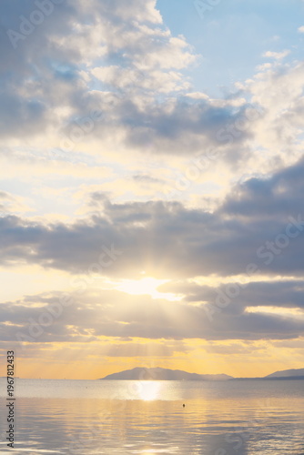 雲間から降り注ぐ光の柱と穏やかな湖辺の夕景 - 山並みのシルエット