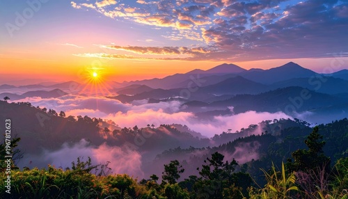 Dawn breaks over misty mountain ranges, sun shining through clouds, scenic landscape