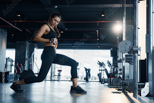 Sporty woman exercising on multistation at gym for arm and shoulders muscles. Fitness exercising in gym.