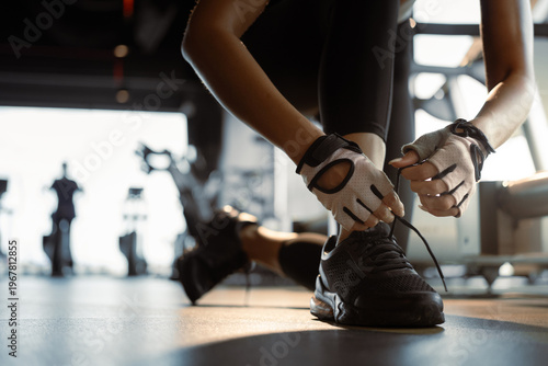 Close-up of sportswoman tying shoelace in a gym.
