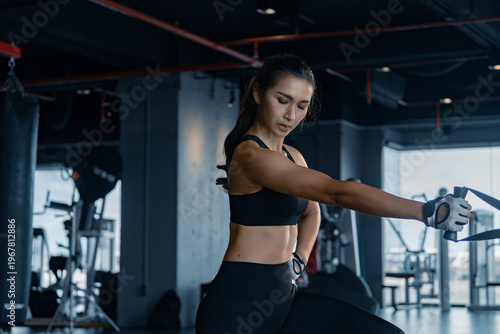 Sporty woman exercising on multistation at gym for arm and shoulders muscles. Fitness exercising in gym.