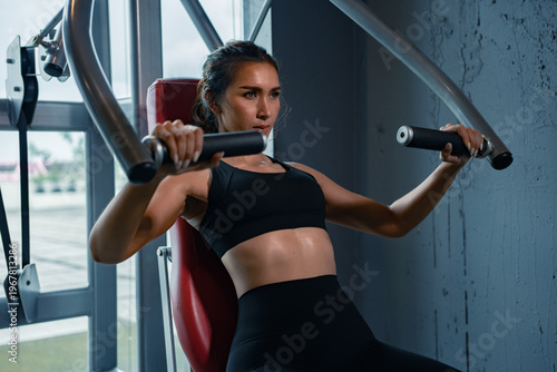 Focused woman trains on gym machine.