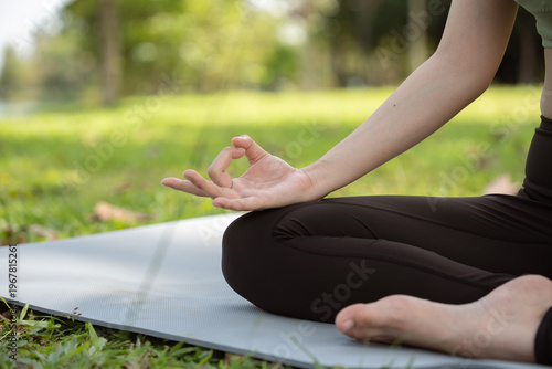 Close up Woman practicing meditating on yoga mat outdoors. Lotus pose. Yoga for health, health and wellness concept.