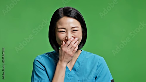 Smiling female nurse in blue scrubs against green background