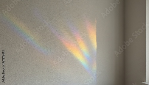 A vibrant rainbow light beam shining on a plain wall from a window