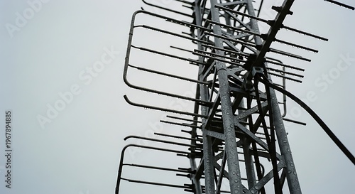Close-up of a weathered metal television antenna mast against a cloudy grey sky