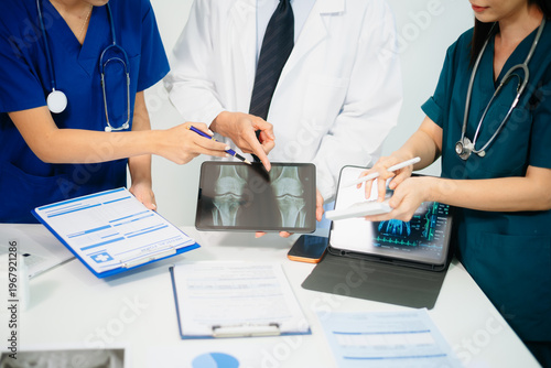 Doctors and nurses analyzing x-ray image on tablet for diagnosis, using digital technology in modern hospital, teamwork