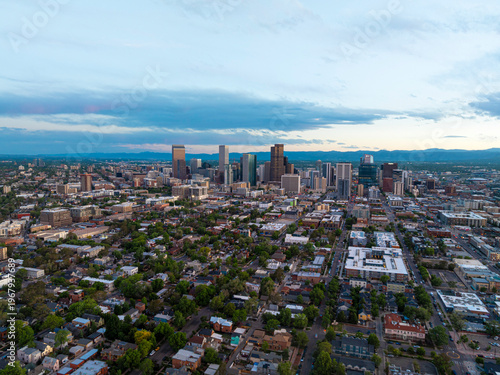 Aerial view of downtown Denver skyline with green neighborhoods under cloudy sky