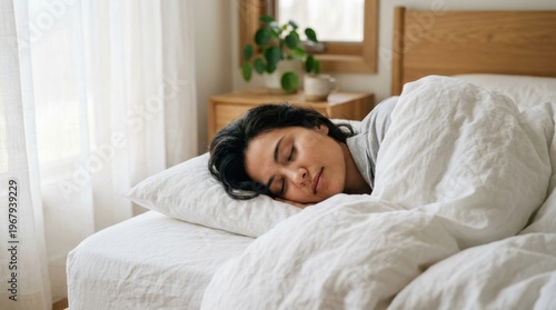 A dark-haired woman peacefully sleeping in a comfortable bed with her eyes closed.
