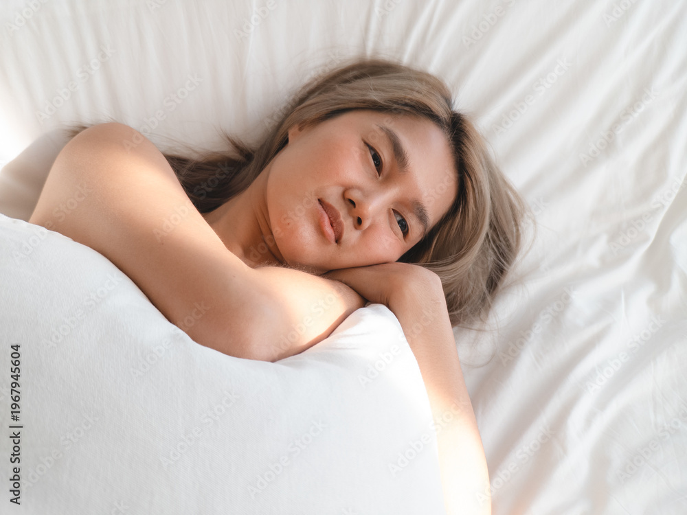 Obraz premium Intimate selfcare scene. Young woman embracing pillow confidently