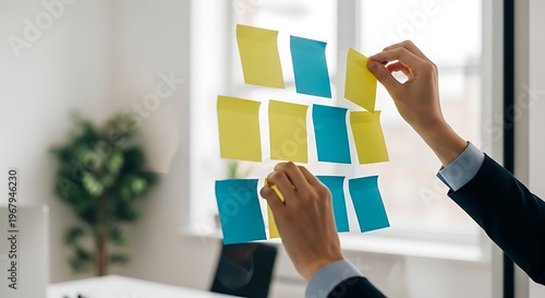 Hands placing colorful sticky notes on an office glass wall