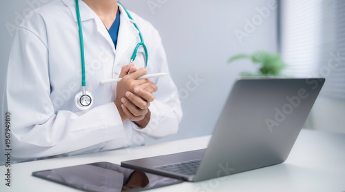 Photography Doctor holding stylus thinking before using laptop in digital healthcare environ