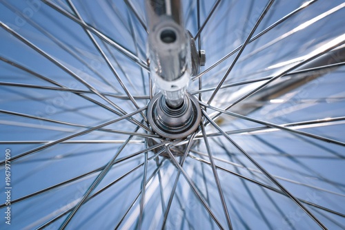 Bicycle wheel hub and shiny spokes forming a radial pattern against a bright blue background, showing engineering and design detail