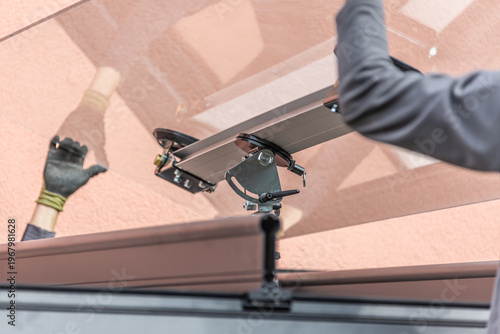 Workers install patio roofing with steel and glass