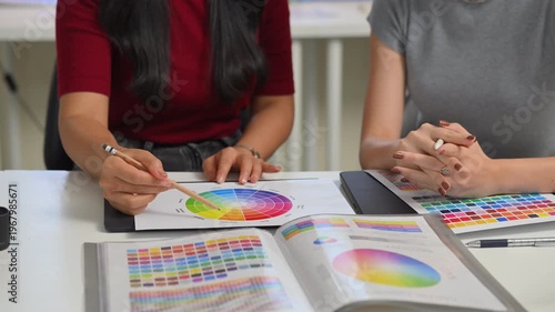 Close up of two young women hands discussing color palette and graphic design samples, creative teamwork and planning process in office..