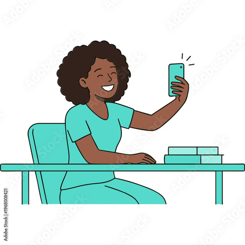 A woman sitting at a desk happily takes a selfie with her phone.