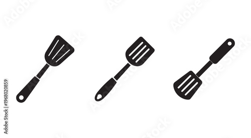 Three black kitchen spatulas with handles and holes isolated on white background for cooking and flipping food  kitchen utensils