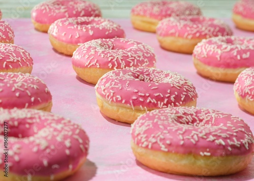 Cuadro en lienzo A vibrant display of fresh pink donuts topped with white sprinkles catches the eye