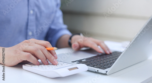 close up accountant woman press on calculator to check about profit or budget and debt of company at office desk for business financial concept