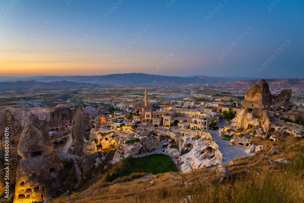 Fototapeta premium Fairy chimneys with the homes carved in a cliffs near Uchisar castle in twilight after sunset. Cappadocia, Turkey.