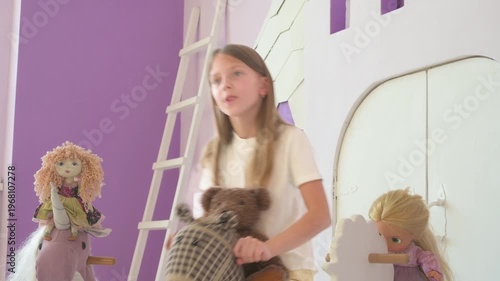 Happy Young Girl Playing with Teddy Bear and Rocking Horses in a Colorful Playroom