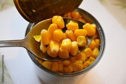 Fotografi Open canned corn with spoon taking portion