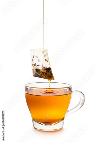 Glass cup of tea with dripping tea bag isolated on white background.