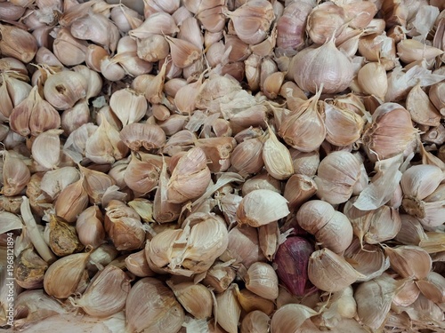 The pile is dominated by garlic (Allium sativum). Most of the garlic cloves are still wrapped in their brownish-white skins. However, if you look closely, you'll notice a single shallot (Allium cepa v